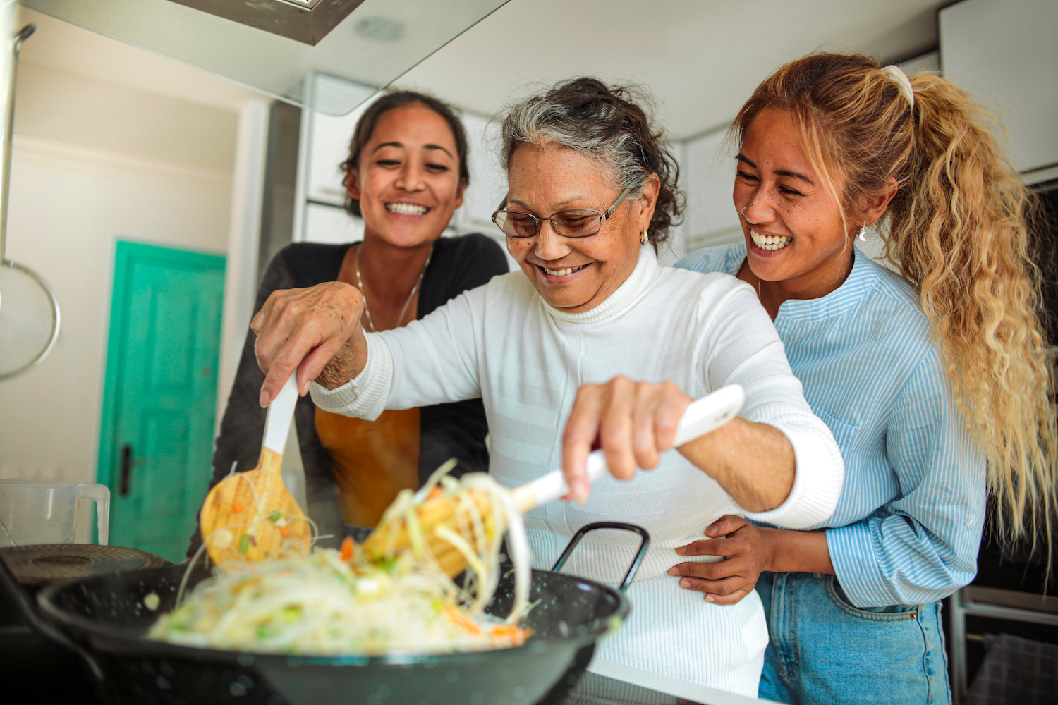Family of three people cooking together at home.